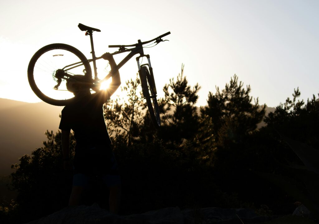 pexels-photo-32351586-32351586 A cyclist lifts a mountain bike with enthusiasm against a sunset backdrop in San Luis Potosí, Mexico.